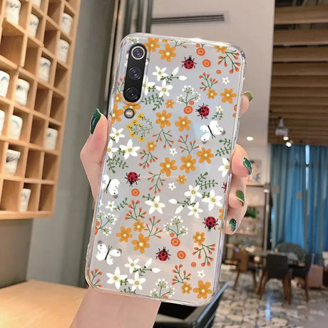 a woman holding a phone case with flowers on it