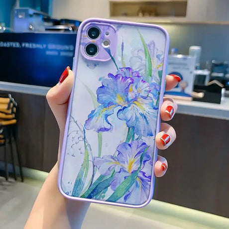 a woman holding a phone case with a watercolor painting on it