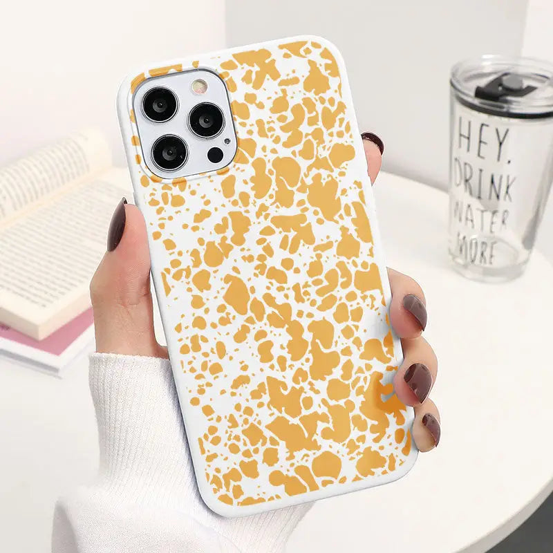 a woman holding a phone case with a yellow and white pattern
