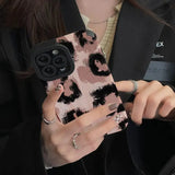 a woman holding a phone case with a pink and black pattern