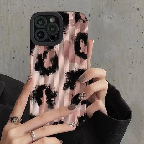 a woman holding a pink phone case with black flowers on it