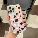a woman holding a pink and black polka dot phone case