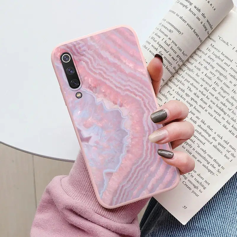 a woman holding a pink marble phone case