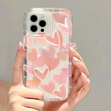 a woman holding a pink heart phone case