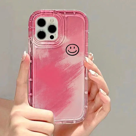 a woman holding a pink iphone case with a smiley face on it