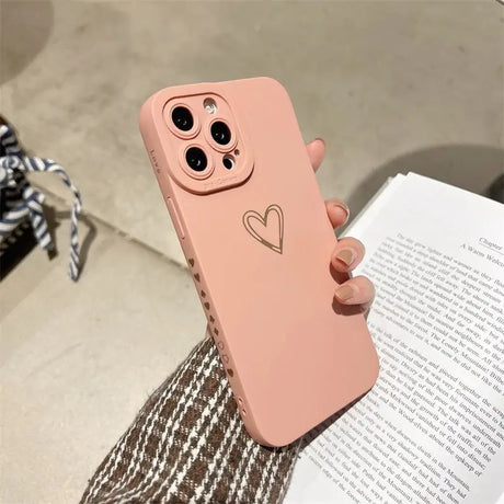 a woman holding a pink iphone case with a heart on it