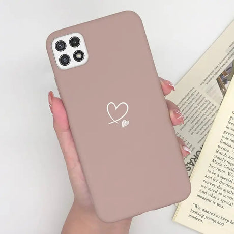 a woman holding a pink phone case with a heart on it