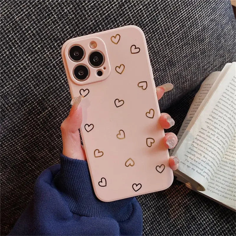 a woman holding a pink iphone case with hearts on it