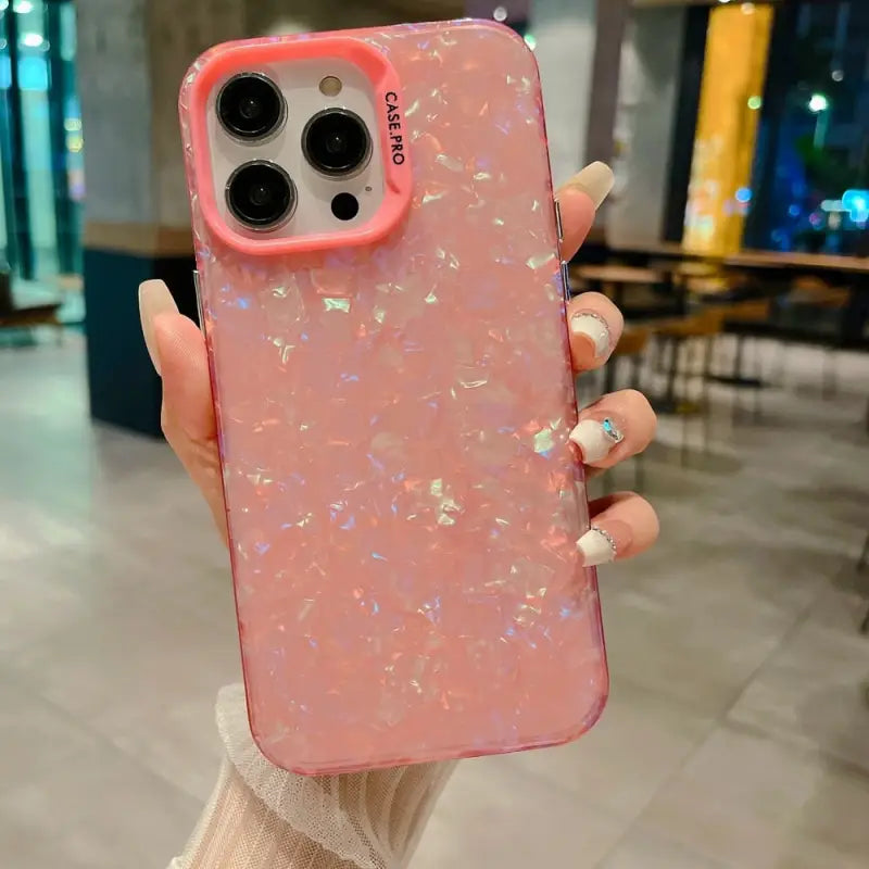 a woman holding a pink phone case with glitter