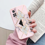 a woman holding a pink marble phone case with a gold geometric design