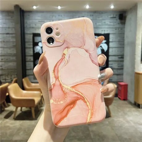 a woman holding up a pink marble phone case