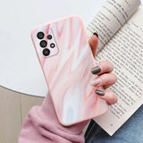 a woman holding a book and holding a pink marble phone case