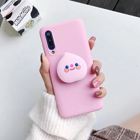 a woman holding a pink phone case with a pig on it