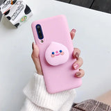 a woman holding a pink phone case with a pig on it