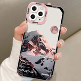 a woman holding a pink phone case with a mountain scene