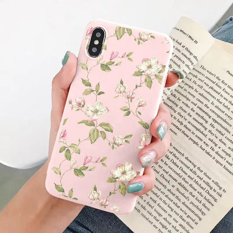 a woman holding a pink phone case with a floral pattern