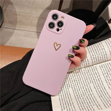 a woman holding a pink phone case with a heart on it