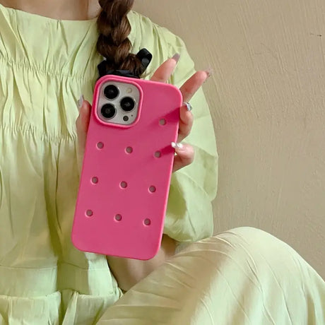 a woman holding a pink phone case