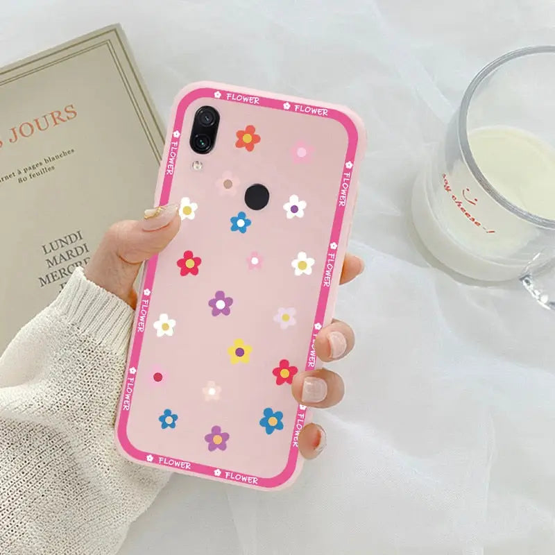 a woman holding a pink phone case with flowers on it