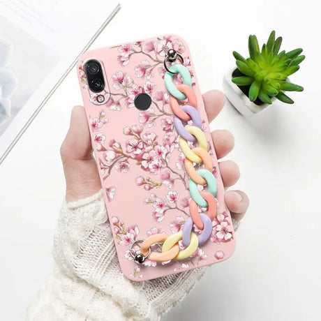 a woman holding a pink phone case with a colorful flower design