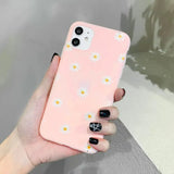 a person holding a pink phone case with daisies on it
