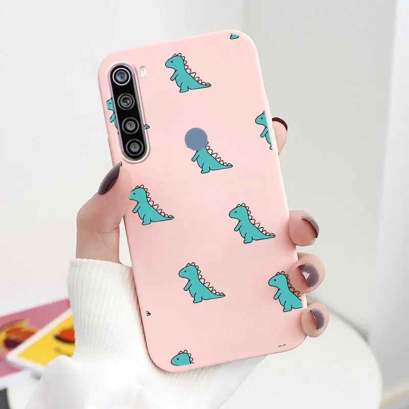 a woman holding a pink phone case with a green dinosaur pattern