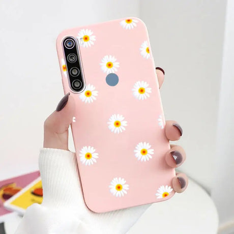 a woman holding a pink phone case with daisies on it