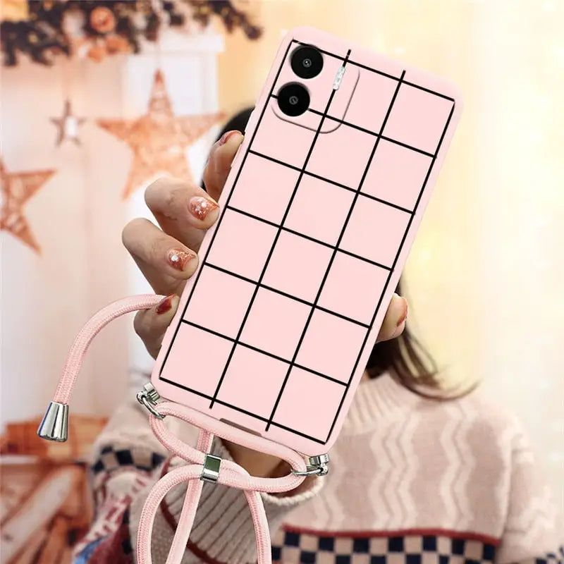a woman holding a pink phone case with a grid pattern