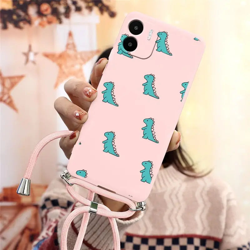 a woman holding a pink phone case with a green dinosaur print