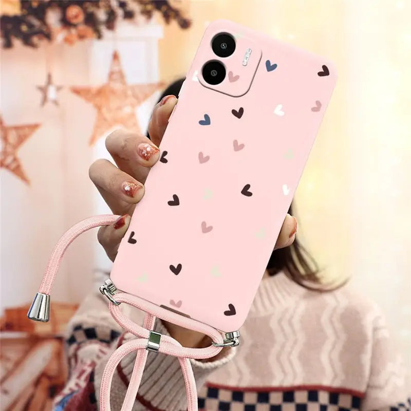 a woman holding a pink phone case with hearts on it