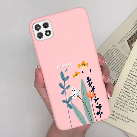 a woman holding a pink phone case with flowers on it