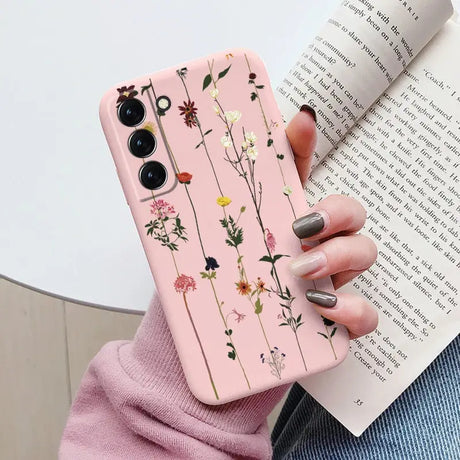 a woman holding a pink phone case with flowers on it