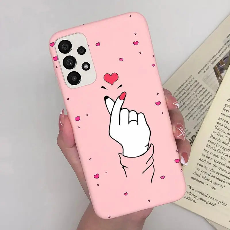 a pink phone case with a heart and a hand holding a finger