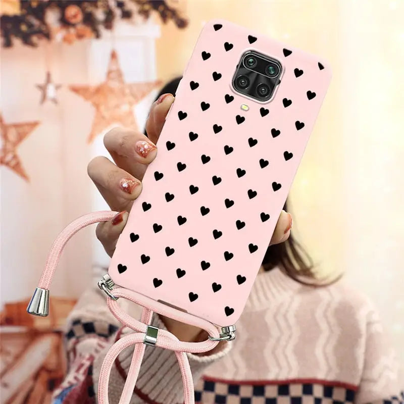 a woman holding a pink phone case with black hearts on it