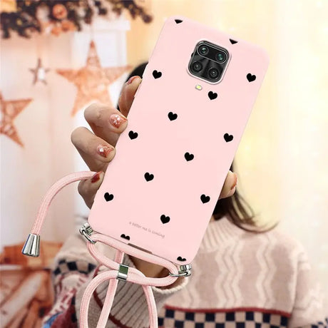 a woman holding a pink phone case with hearts on it