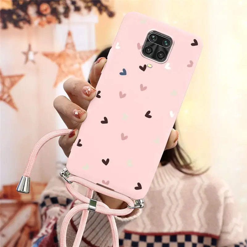 a girl holding a pink phone case with hearts on it