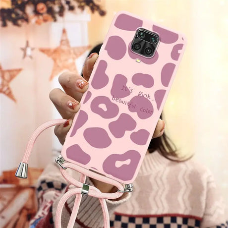 a woman holding a pink phone case with a pink leopard print