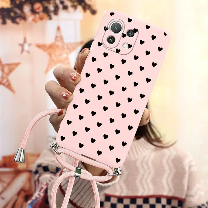 a woman holding a pink phone case with hearts on it