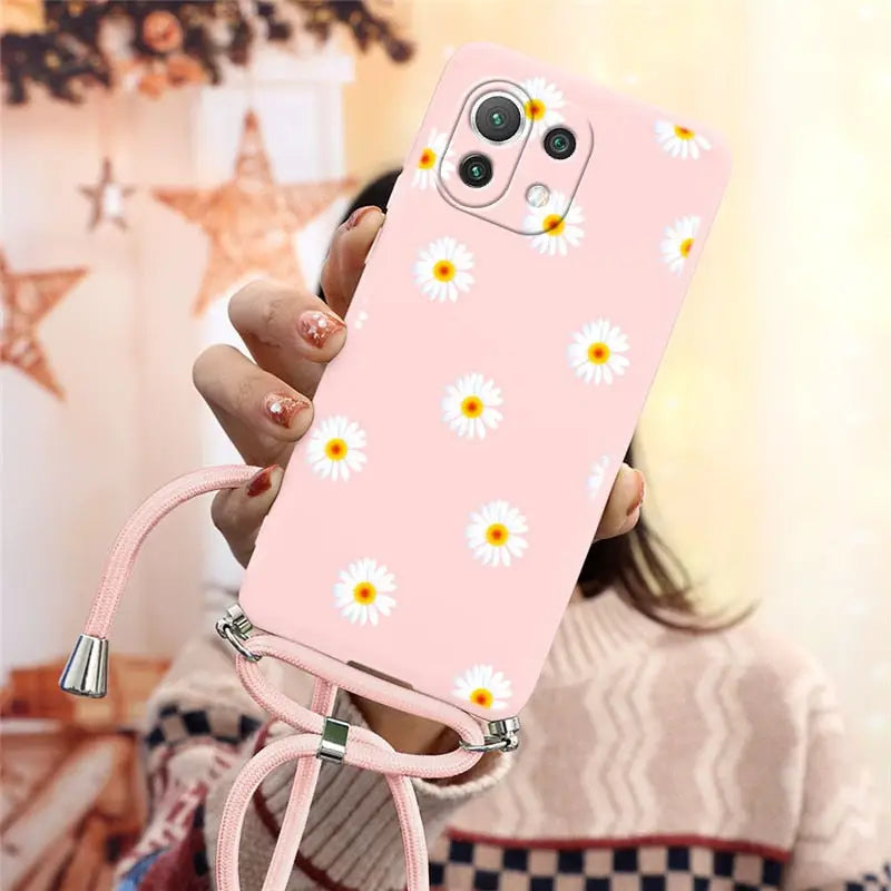 someone holding a pink phone case with daisies on it