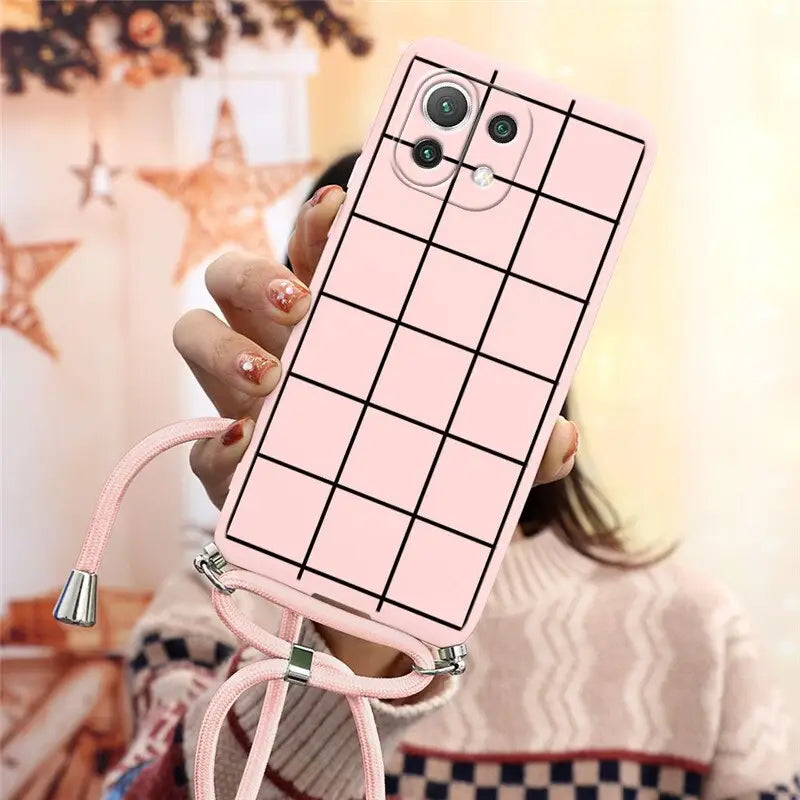 a woman holding a pink phone case with a grid pattern