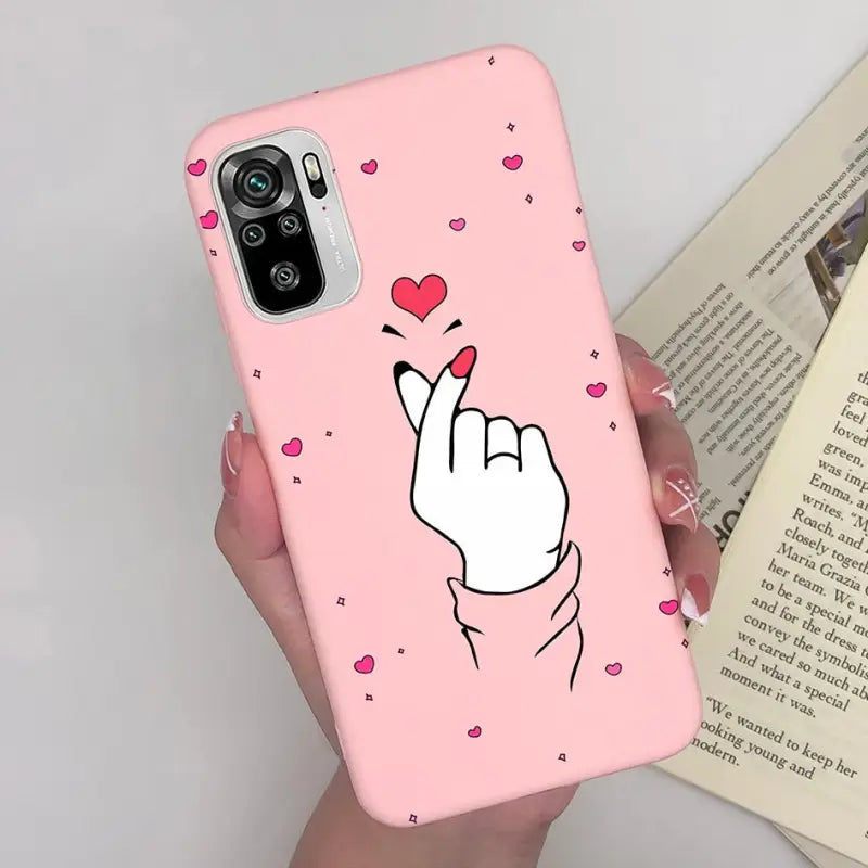 a woman holding a pink phone case with a heart on it