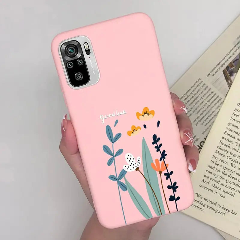 a woman holding a pink phone case with flowers on it