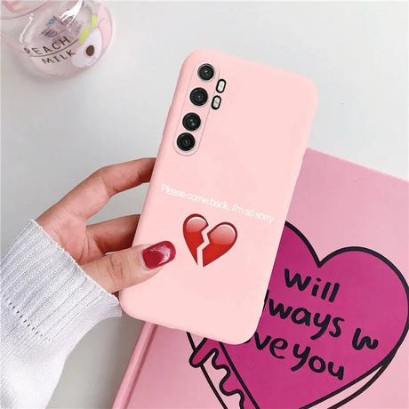 a woman holding a pink phone case with a heart