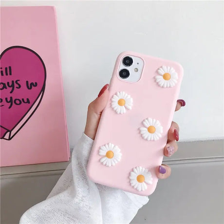 someone holding a pink phone case with daisies on it