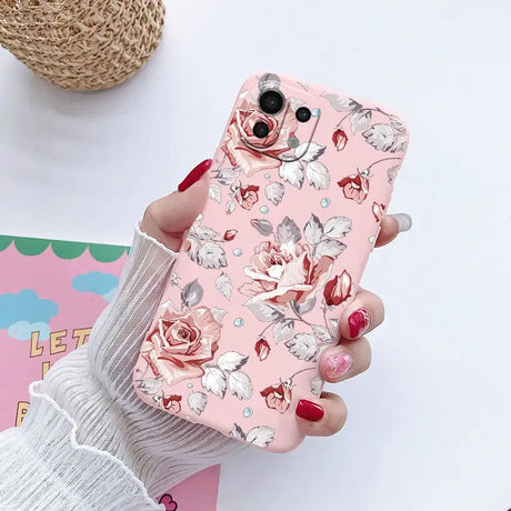 a woman holding a pink phone case with flowers on it