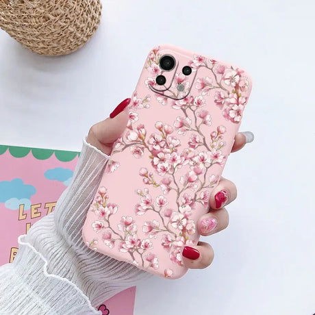 a woman holding a pink phone case with a pink flower design