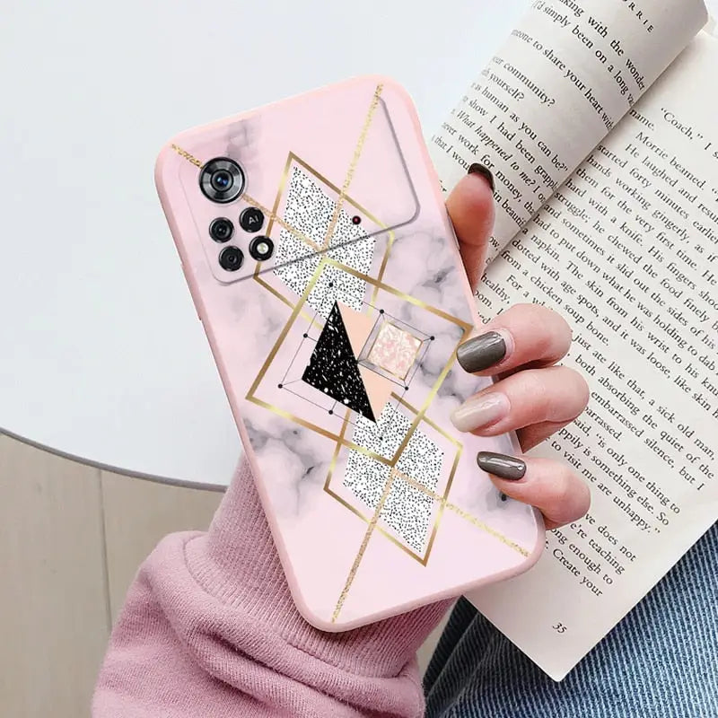 a woman holding a pink marble phone case with gold geometric design