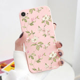 a woman holding a pink phone case with white flowers on it