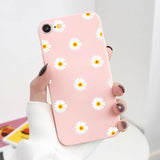 a woman holding a pink phone case with white daisies on it