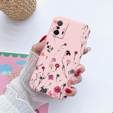 a woman holding a pink phone case with flowers on it